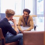 Male College Student Meeting With Campus Counselor Discussing Mental Health Issues