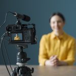 Smiling woman sitting in front of a camera and making a video blog
