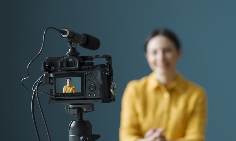 Smiling woman sitting in front of a camera and making a video blog