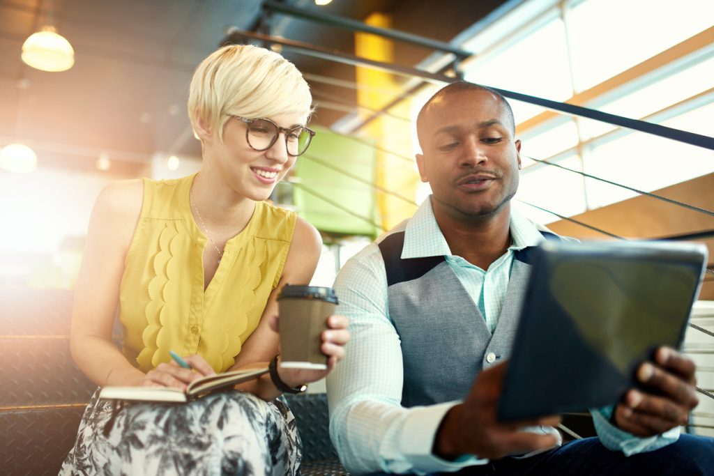 man and woman looking at tablet together in office
