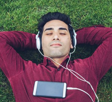 Young man relaxing in the park and listening music