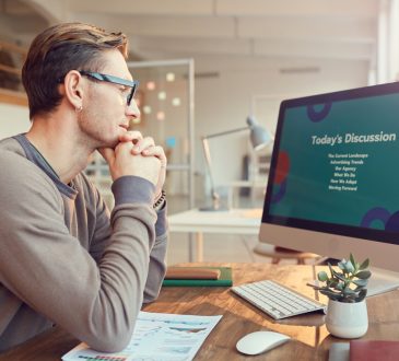 Side view portrait of adult businessman looking at computer screen while preparing for presentation or online conference