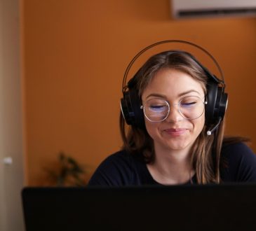 woman wearing headphones working on laptop