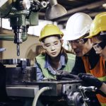 technician manager showing case study of factory machine to two engineer trainees