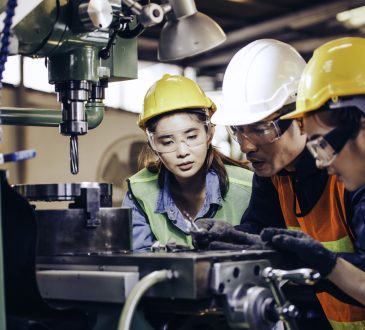 technician manager showing case study of factory machine to two engineer trainees