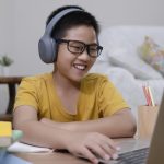 Cheerfully boy excited using computer online learning schoolwork.