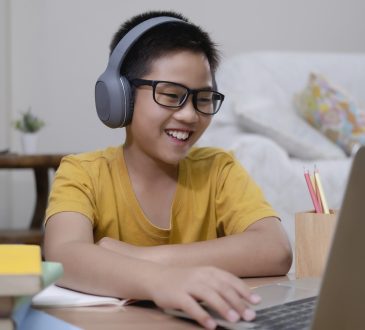 Cheerfully boy excited using computer online learning schoolwork.