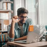 male student looking at laptop in library
