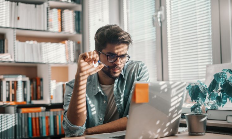 male student looking at laptop in library