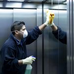 Male cleaner disinfecting elevator