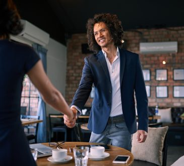 man and woman shaking hands in cafe