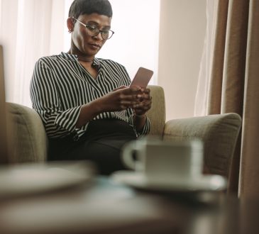 woman reading on cellphone on couch