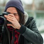 young person taking photo with dslr camera outside