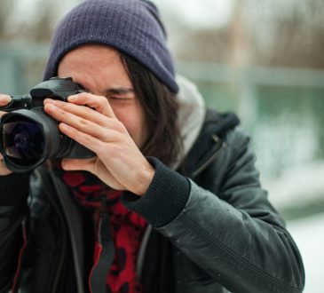 young person taking photo with dslr camera outside