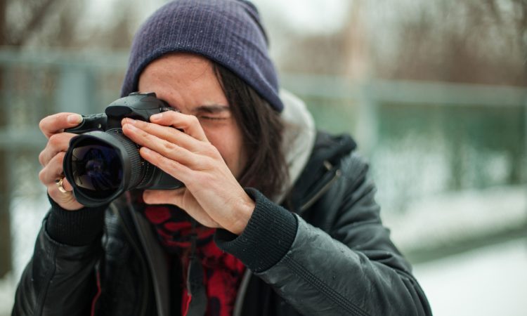 young person taking photo with dslr camera outside