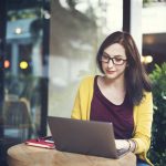 woman using laptop on cafe table