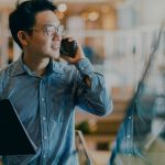 man holding clipboard and talking on cellphone in office
