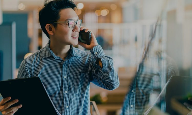 man holding clipboard and talking on cellphone in office