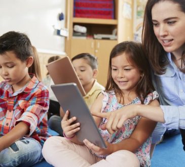 teacher sitting with young students on classroom floor