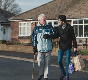 young man helping old man carry groceries