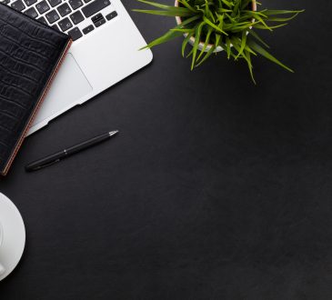 Office leather desk workplace table with laptop, coffee cup, notepad and plant.