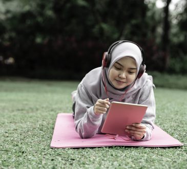 student lying on grass looking at tablet