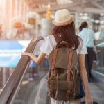 woman with backpack in airport terminal on escalator