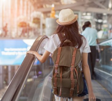 woman with backpack in airport terminal on escalator