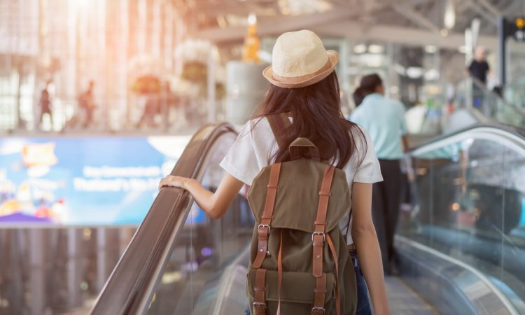 woman with backpack in airport terminal on escalator