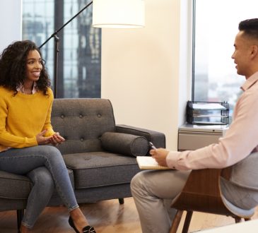Woman Sitting On Couch Meeting With Male Counsellor In Office