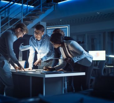 group of engineers working around table in office at night