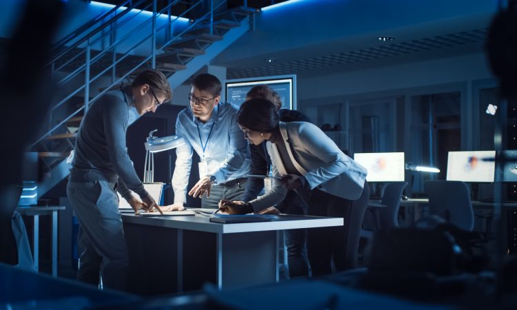 group of engineers working around table in office at night