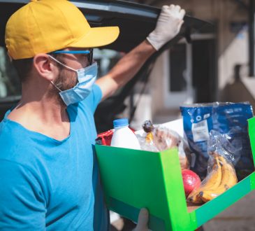 Delivery guy with protective mask and gloves delivering groceries during lockdown and pandemic.