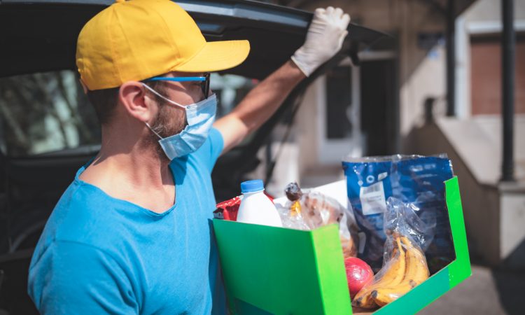 Delivery guy with protective mask and gloves delivering groceries during lockdown and pandemic.