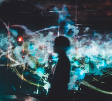 person silhouetted on background with colourful light patterns