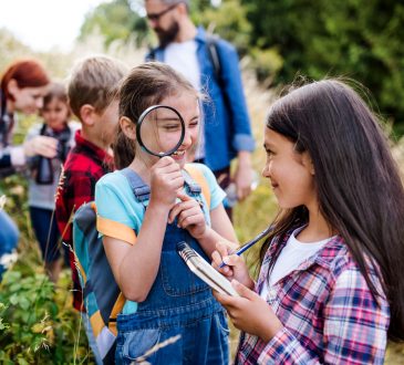 A group of small school children with teacher on field trip in nature