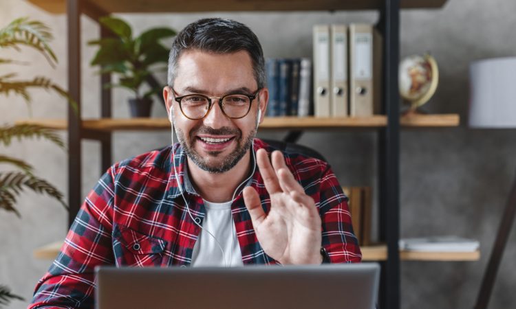 Middle aged man having video call from workplace at home