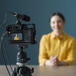 Smiling woman sitting in front of a camera and making a video blog