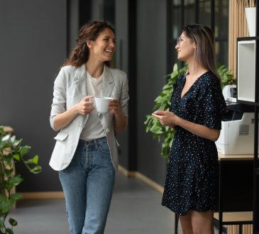 two women co-workers laughing and talking in office