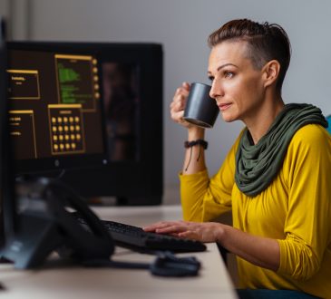 Businesswoman wearing yellow shirt working in the office and drinking coffee