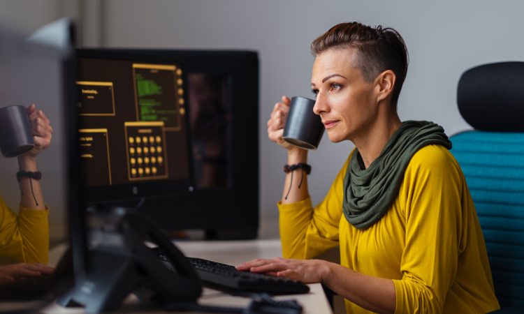 Businesswoman wearing yellow shirt working in the office and drinking coffee