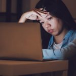 woman working at night on laptop looking stressed