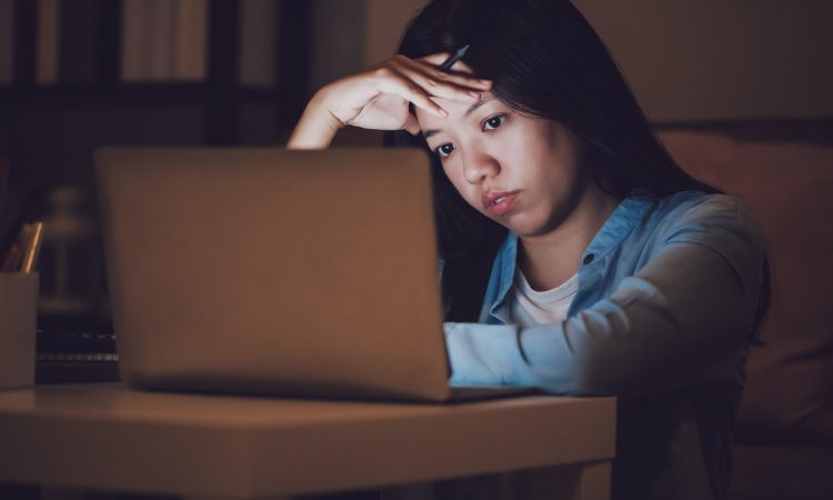 woman working at night on laptop looking stressed