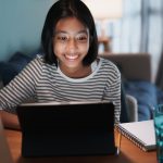 teen girl smiling while looking at tablet