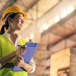 female engineer inspector wearing hard hat and holding clipboard