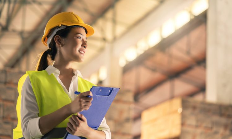 female engineer inspector wearing hard hat and holding clipboard
