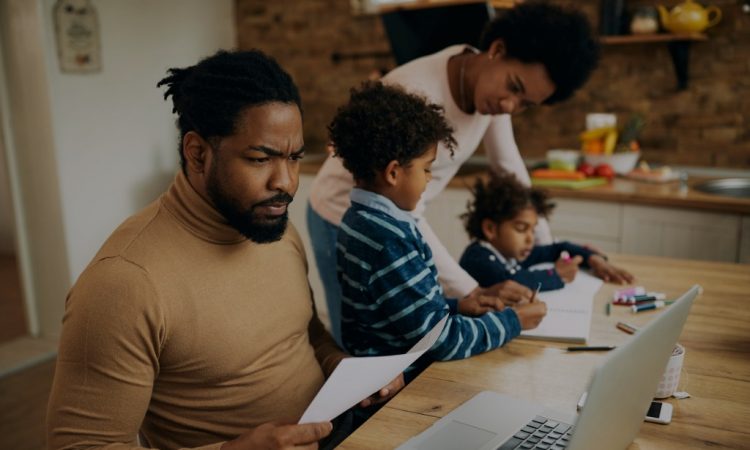 dad working while mom homeschools kids at kitchen table