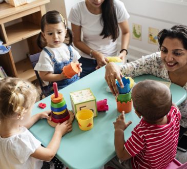 Nursery children playing with teacher in the classroom
