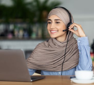 woman wearing headset and smiling at laptop screen
