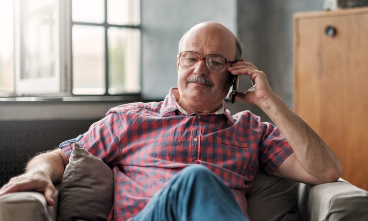 man talking on phone sitting at living room.